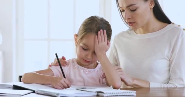 Worried teacher mom supporting upset child daughter doing difficult homework - Imágenes, Vídeo