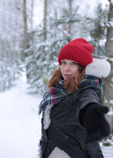 junge Frau mit Ingwerhaaren bei einem Winterspaziergang im Wald bei kaltem Wetter und guter romantischer Stimmung - Foto, Bild