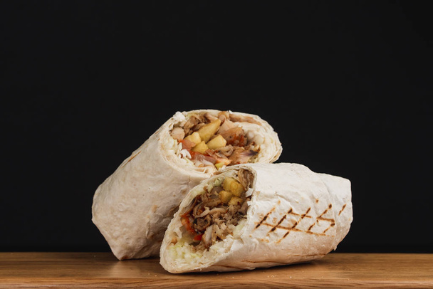 Shawarma sendvič, čerstvý rohlík nastříhaný na dva kusy, na černém pozadí - Fotografie, Obrázek
