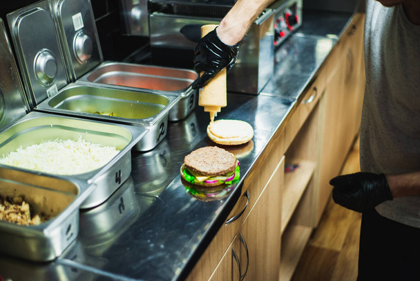 közelkép, férfi készül finom hamburger és hozzá néhány mustár - Fotó, kép