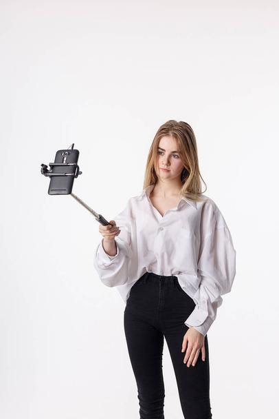 young pretty girl making self portrait with smartphone attached to selfie stick - Fotoğraf, Görsel