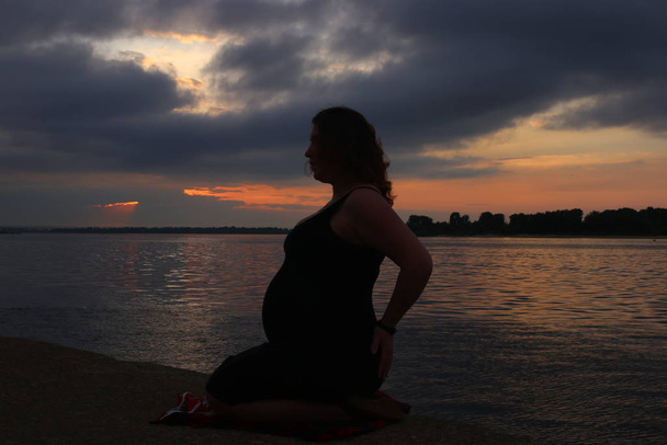 Hamileliğinin dokuzuncu ayında kıvırcık kızıl saçlı genç bir kadın. - Fotoğraf, Görsel