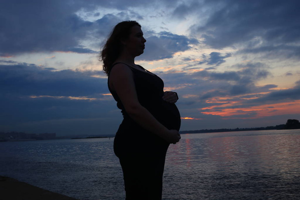 młoda kobieta z kręconymi rudymi włosami w dziewiątym miesiącu ciąży - Zdjęcie, obraz
