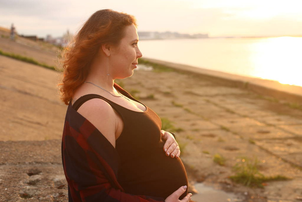 jovem com cabelo encaracolado vermelho no nono mês de gravidez
 - Foto, Imagem