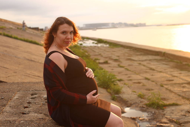 jonge vrouw met krullend rood haar in de negende maand van de zwangerschap - Foto, afbeelding