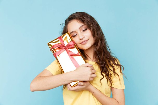 Beautiful young lady holding present box in the blue studio. - Zdjęcie, obraz