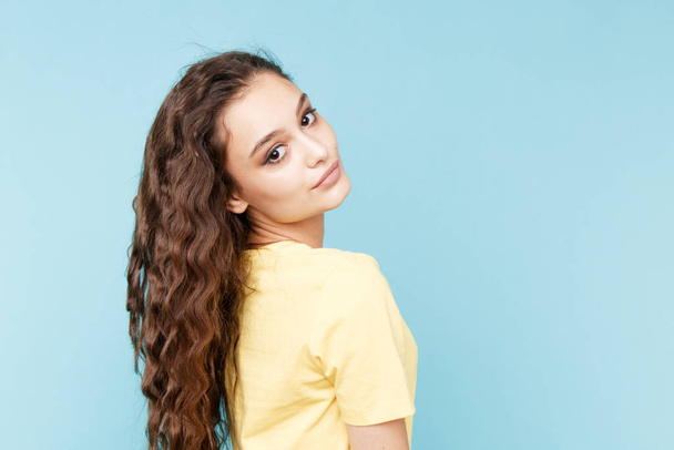 Beauty casual fasion portrait. Curly hair nice woman posing isolated over the blue background. - Photo, Image