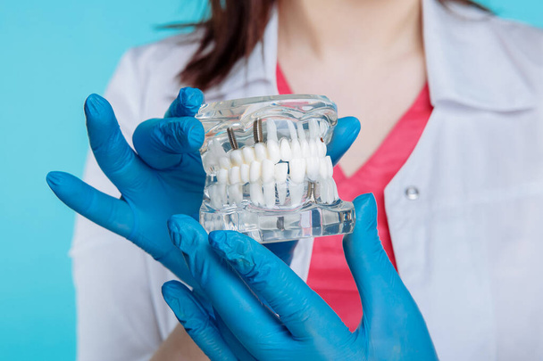 close up foto de mãos em luvas segurando placa dental isolado sobre o fundo azul
. - Foto, Imagem