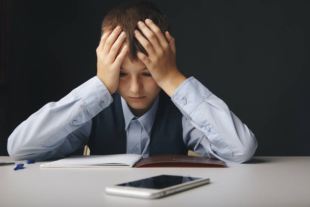 Cyberbullying concept. Stressed and upset school boy with gadget isolated. - Photo, Image