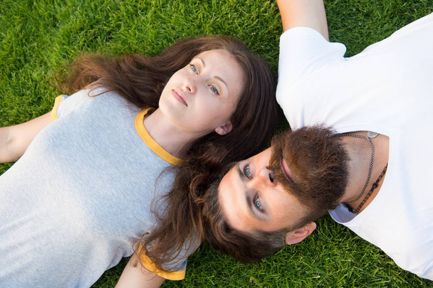 couple lie on green grass. man and woman relax outdoor. dreaming concept. Dating concept. bearded hipster and girl carefree. Youth and freedom. Closer to nature. couple feel free. Freshness and peace - Fotoğraf, Görsel