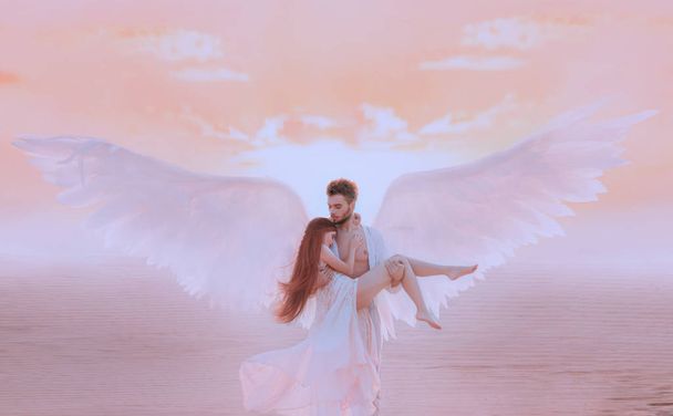 Strong muscular male angel holds hug fragile innocent woman in arms. concept protection prayer security helper keeper love faith help religion. Fine art imagery sky. Girl and handsome man embracing - Photo, image