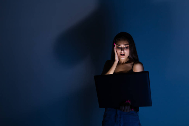 грустный и женский подросток с планшетным компьютером и ноутбуком страдает от кибериздевательств и домогательств в сети, над которыми издевается преследователь или сплетница, чувствуя себя отчаявшейся и униженной в кибер-издевательствах
. - Фото, изображение