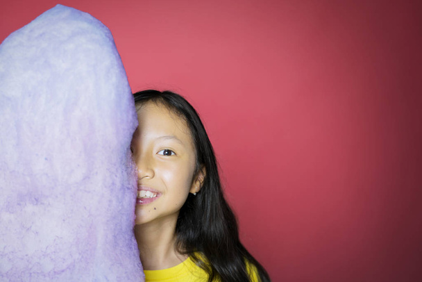 Girl smiling and covering her face behind a candy - Photo, Image