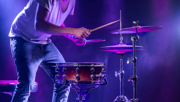 Um baterista toca bateria em um fundo azul. Lindo ef especial
 - Foto, Imagem