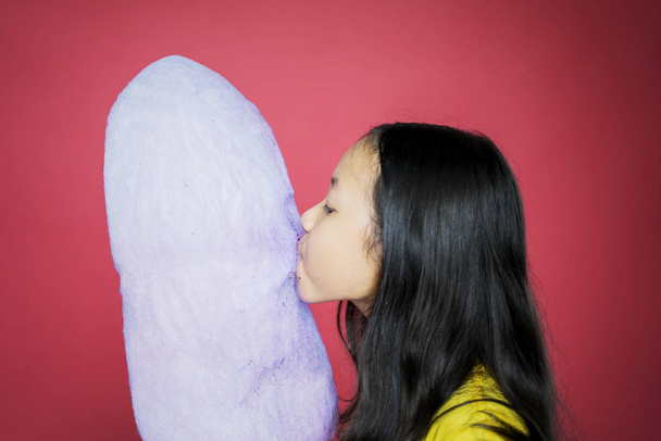Side view of girl eating and biting a cotton candy - Photo, Image