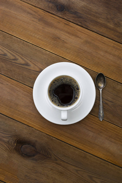 Kubek kawy izolowany na drewnianym stole. Widok z góry, płaski leżał napój kawowy z przestrzenią do kopiowania. Obraz pionowy. - Zdjęcie, obraz