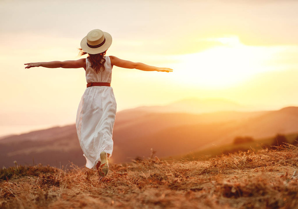   Mulher feliz de pé com as costas no pôr do sol na natureza
   - Foto, Imagem