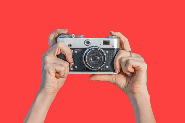 赤い背景に孤立したレトロカメラを持つ女の手 - 写真・画像
