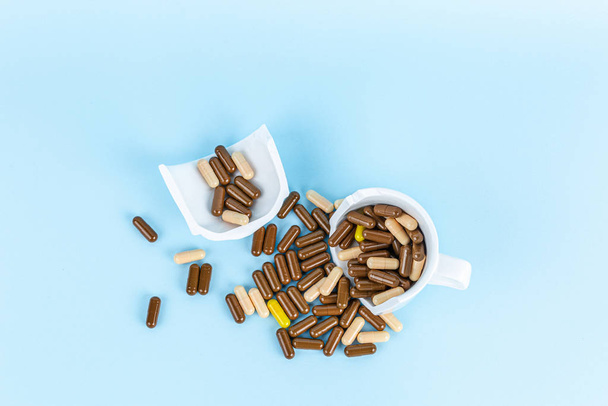 pills in broken white cup, flat lay - Фото, изображение