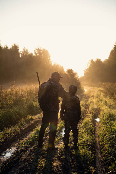 Отец учит своего внука охотиться в лесу
 - Фото, изображение