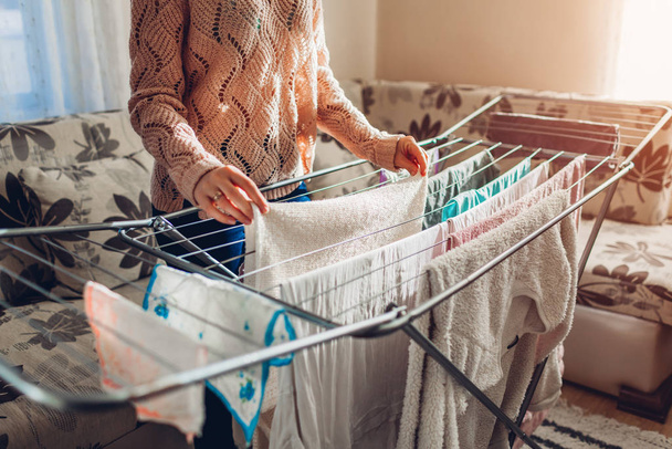 Evde yıkandıktan sonra temiz çamaşırları kurutucuya asan bir kadın. Oda servisi ve ev işleri. - Fotoğraf, Görsel