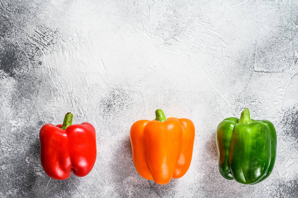 Green, orange and red bell peppers. Gray background. Top view. Space for text. - Zdjęcie, obraz