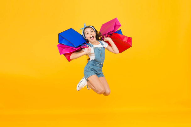 Towards discounts. Happy girl jump with shopping bags. Little child smile with paper bags. Holidays preparation and celebration. Shopping on black friday. Inspiring shopping. Trends and brands - Fotó, kép