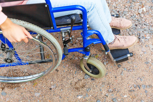 患者サービスを待っている病院の公園の道路上の車椅子の車輪の足のハンディキャップの女性。屋外の障害者のための無効な椅子の認識できない麻痺した少女。リハビリテーションの概念. - 写真・画像