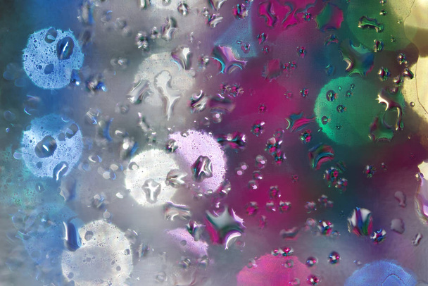 Macro abstracte kunst textuur van water druppels condenseren op een glazen oppervlak met kleurrijke onscherpe kralen bokeh op de achtergrond - Foto, afbeelding