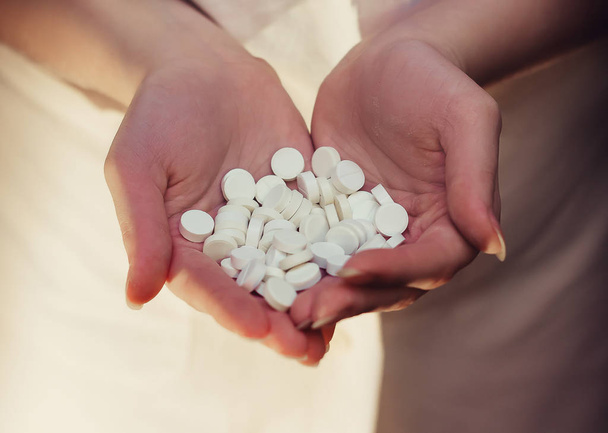 Une poignée de pilules blanches dans les mains des femmes. Beaucoup de pilules dans les paumes. Le concept de maladie, de régime, de médecine
 - Photo, image