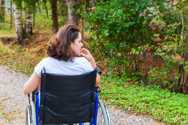 Giovane donna handicappata felice in sedia a rotelle su strada nel parco ospedaliero godendo della libertà. Ragazza paralizzata in sedia non valida per disabili all'aperto in natura. Concetto di risanamento. - Foto, immagini