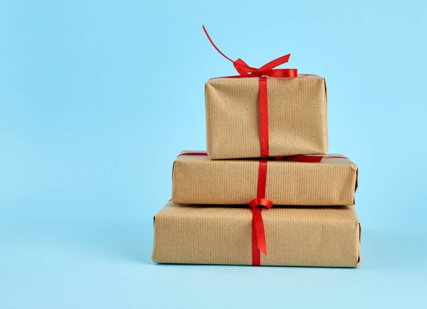 pile de boîtes enveloppées dans du papier brun et attachées avec un noeud rouge
 - Photo, image
