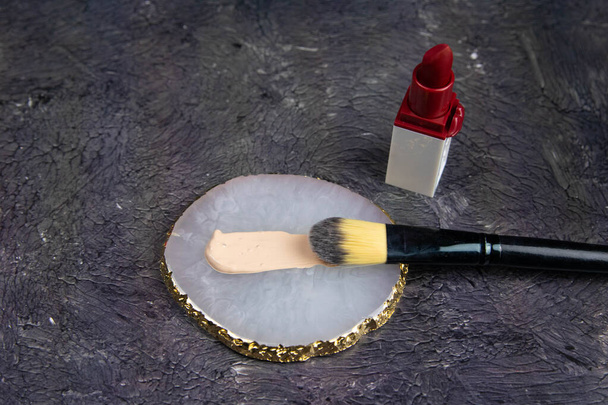 Makeup foundation brush blur cream and lipstick on the black background. - Photo, Image