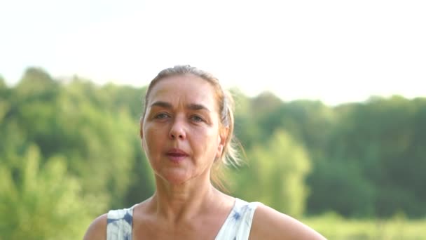 Portret van een vrouw van middelbare leeftijd die glimlacht en in slow motion een luchtkus stuurt. - Video