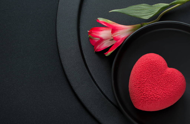 День святого Валентина концепция. Бархатный торт с красным сердцем на черном фоне с нежным цветком альстромерии
 - Фото, изображение