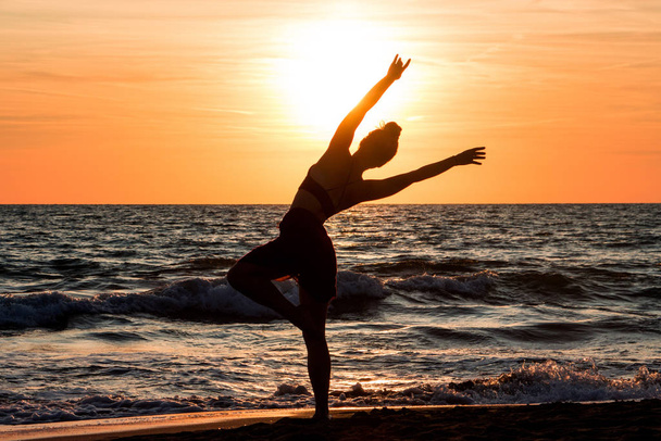 Lonely Dancer ballet poseren op het strand zonsondergang silhouet zee - Foto, afbeelding