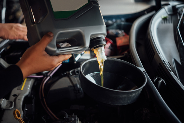 Car mechanic fills a fresh lubricant engine oil - Foto, immagini