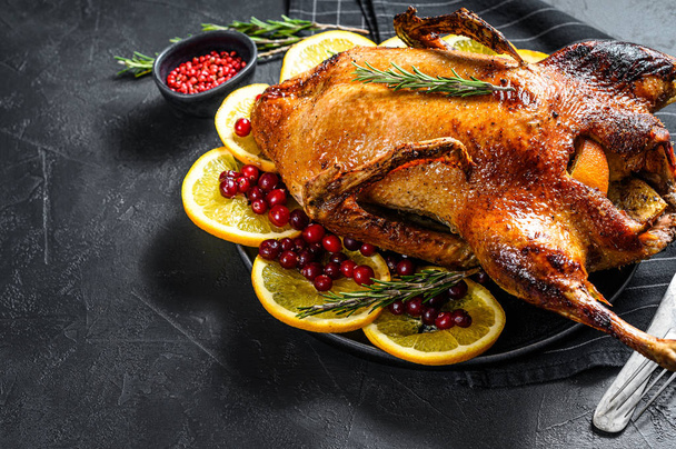 Baked goose stuffed with oranges and rosmarina. Festive table. Black background. Top view. Space for text - Photo, Image