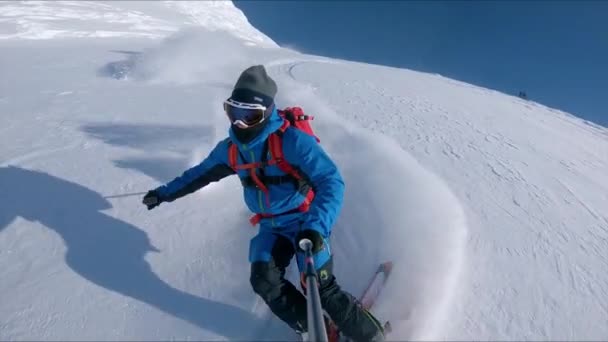 Slow Motion: Extreme freeride skiër verscheurt de sneeuw van de piste op een zonnige dag. - Video
