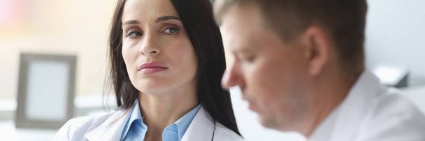 Frau sieht unzufriedenen Arzt misstrauisch an - Foto, Bild