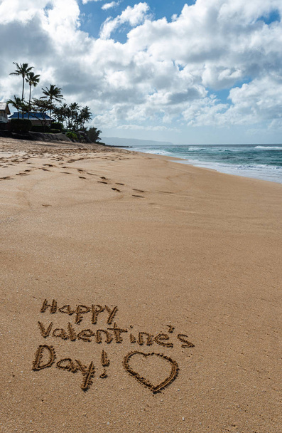 Gelukkige Valentijnsdag met een hart getekend in het zand op het strand - Foto, afbeelding