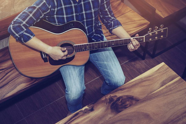 Widok z góry człowieka gra na gitarze akustycznej na drewnianym krześle w biurze - Zdjęcie, obraz
