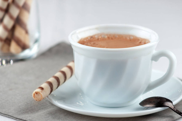 On the table is a cup of fresh aromatic coffee with sweet tubes - Φωτογραφία, εικόνα
