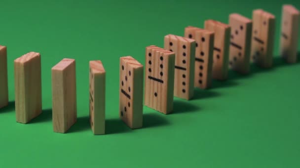Houten dominostenen staan in de rij voor een domino show, en snel neergehaald. Ze staan tegen een groene achtergrond met uitgesproken schaduwen. - Video
