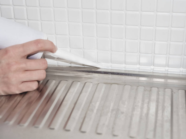 Utilizzando adesivo siliconico per l'installazione di un lavandino in cucina. Servizio professionale di riparazione uomo fornendo mobili installare a casa
 - Foto, immagini