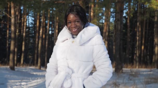 negro chica poses cogidas de la mano en bolsillos contra snowy park - Metraje, vídeo