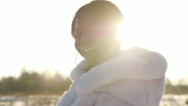 sorridente ragazza dalla pelle scura posa contro campo innevato vuoto - Filmati, video