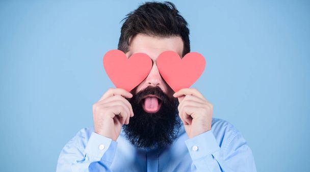 Love is blind. Hipster covering eyes with small hearts. Sexy valentine man with heart shaped decorations. Happy valentines day. Bearded man holding red hearts. The holiday of love and romance - Foto, imagen