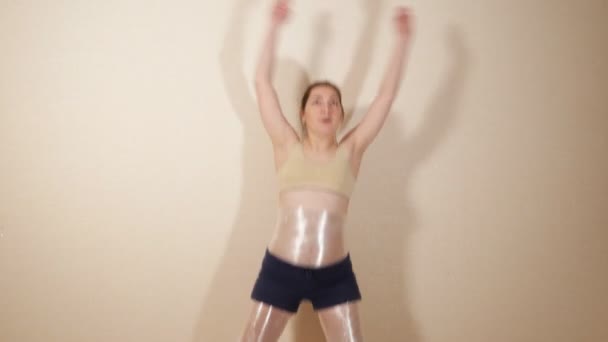 brunette does sports exercises, wrapping the problem areas with plastic wrap - Záběry, video