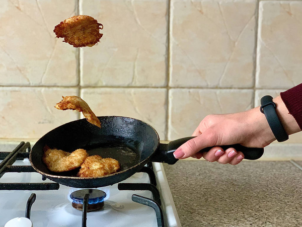Potato pancakes in the cooking process. Fried pancakes in an old pan, on a gas stove. Cooked pies in a pan in sunflower oil.  - Photo, Image